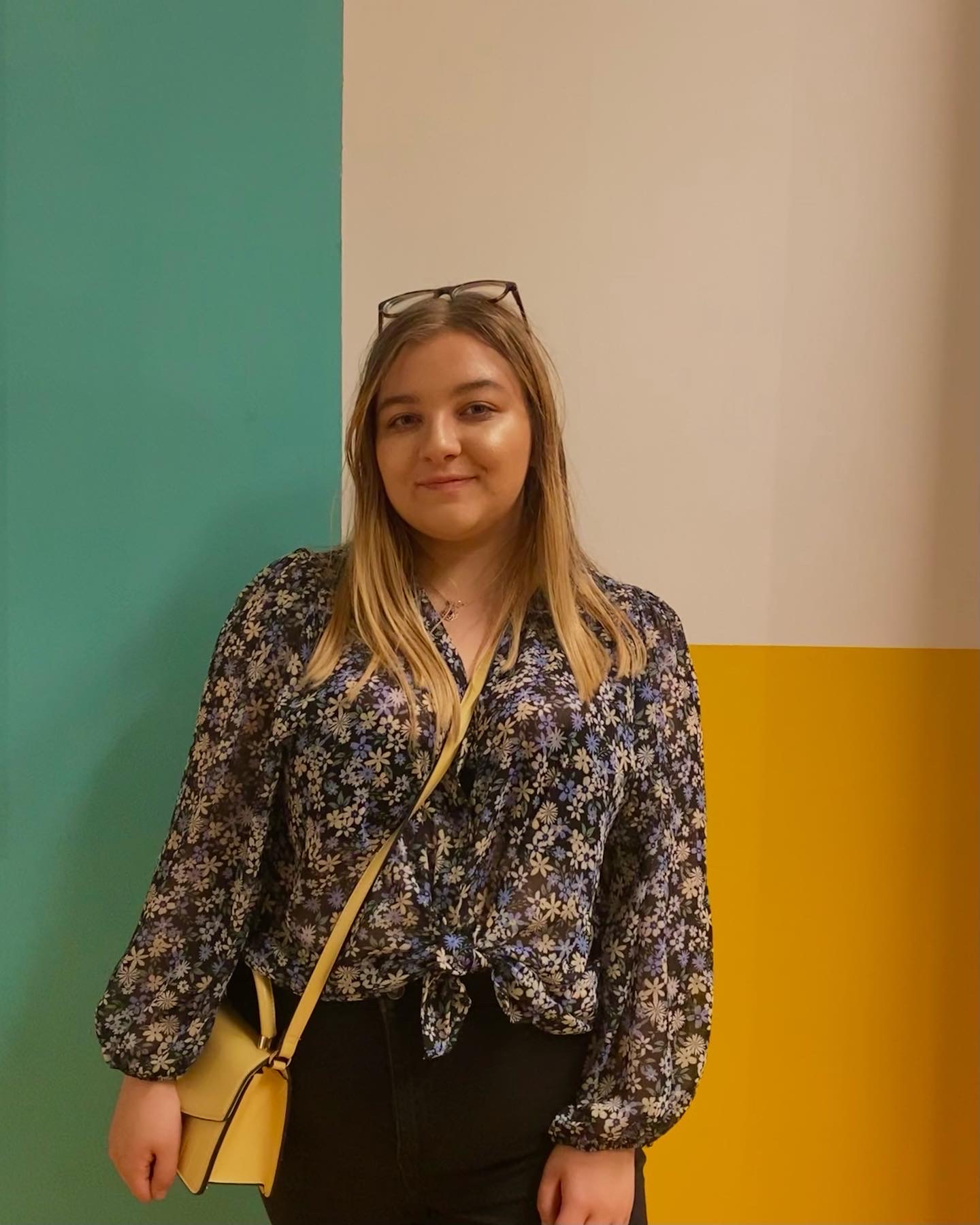 A student standing against a colourful wall